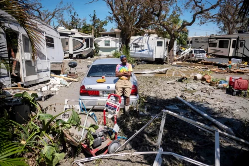 A man sits on his damaged car in front of his camper in Fort Myers, Fla., on Thursday, after Hurricane Ian hit the state.  (Ricardo Arduengo / AFP via Getty Images)