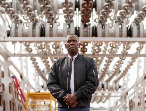 Charles Gaines with his piece Moving Chains in "Charles Gaines: The American Manifest, Moving Chains" on Governors Island. (Photo by Timothy Schenck, courtesy of Creative Time).