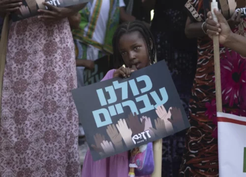 Screen-Shot-2023-11-15-at-5.07.32-PM-1 A child from the Hebrew Israelite community holds a placard that reads "We are all Hebrew," at a rally outside of the District Court in Beersheba, Israel, in July 2023. (AP Photo/Maya Alleruzzo)