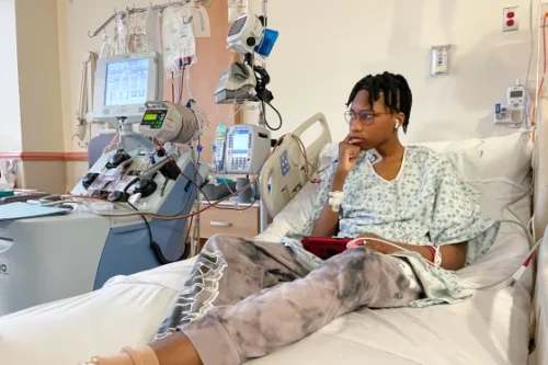 Wedam Minyila spent hours on his phone or sleeping during his stem cell collection, as an apheresis machine drew his blood out of his body, spun out the stem cells and then returned the blood back into his veins. (Jason Kane / NBC News)