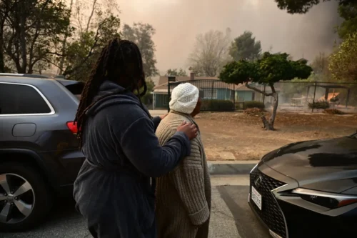 A woman is aided by her family as she leaves her home during the Eaton Fire in Altadena, California, on Jan. 8. More than 1,000 buildings have burned in multiple wildfires that have erupted around America's second-biggest city, forcing tens of thousands of people from their homes. (Robyn Beck/AFP)