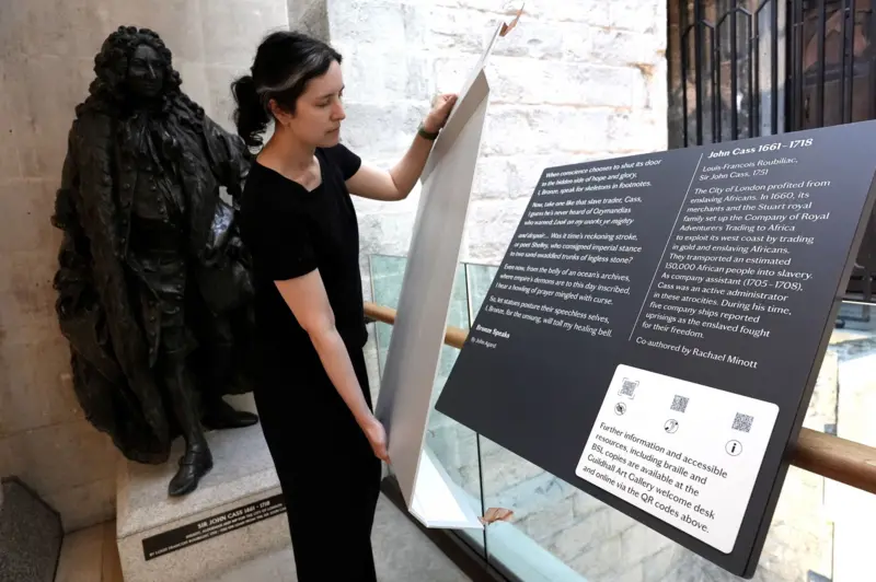 A plaque condemning slave traders is attached to a statue of John Cass