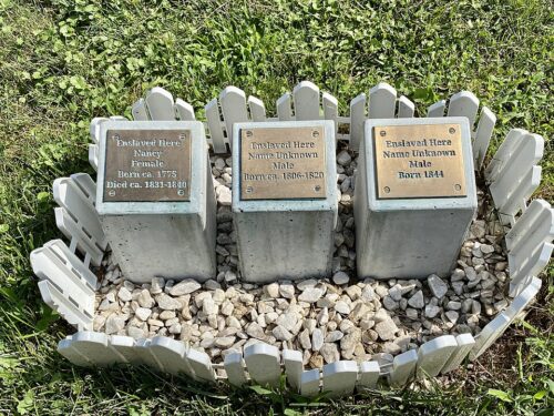 Three raised stones with metallic plaques depicting names of slaves