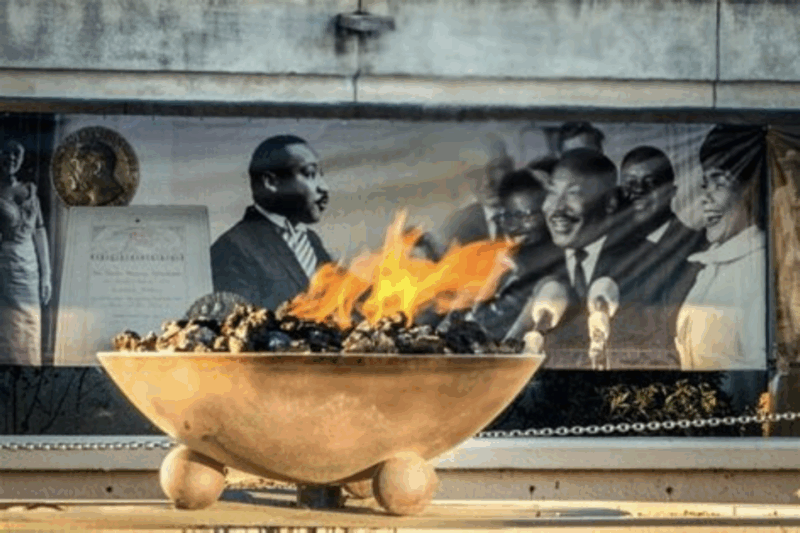 The eternal flame burning in front of a mural of Martin Luther King Jr