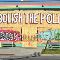 Graffiti on a temporaty wooden wall saying "Abolish the police"