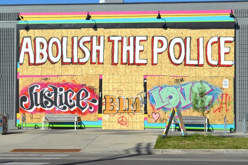 Graffiti on a temporaty wooden wall saying "Abolish the police"